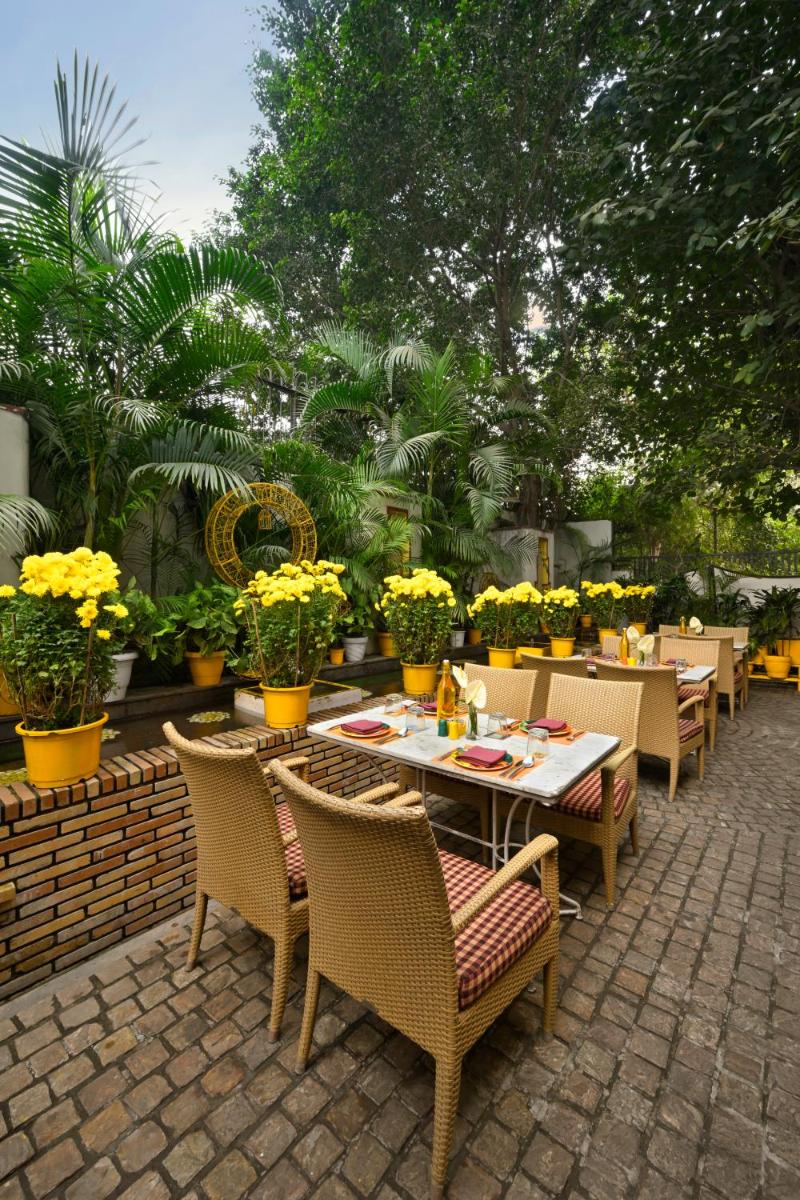 a patio with tables and chairs and yellow flowers at Ambassador, New Delhi - IHCL SeleQtions in New Delhi a patio with tables and chairs and yellow flowers at Ambassador, New Delhi - IHCL SeleQtions in New Delhi