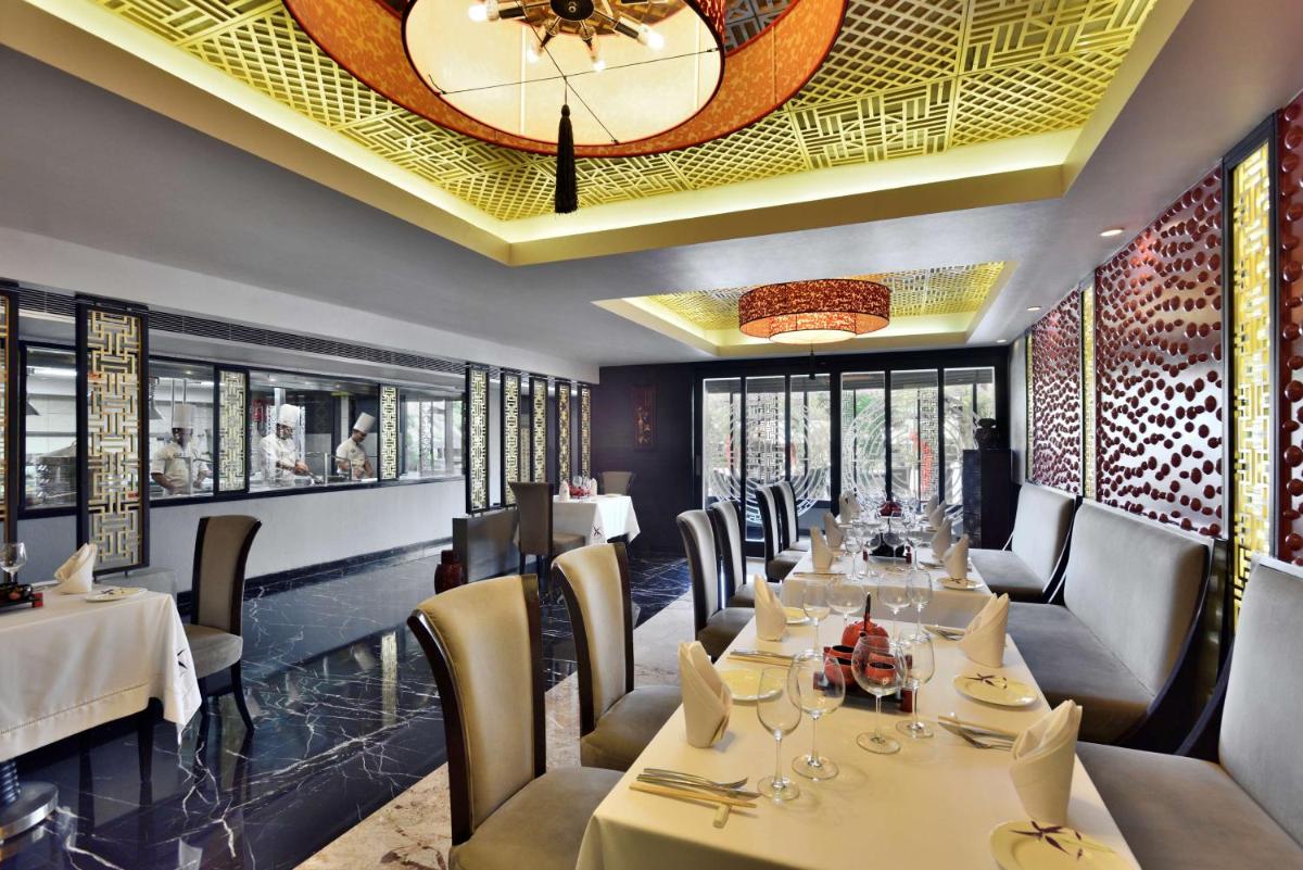 a restaurant with tables and chairs and a ceiling at Radisson Blu Hotel, Indore in Indore