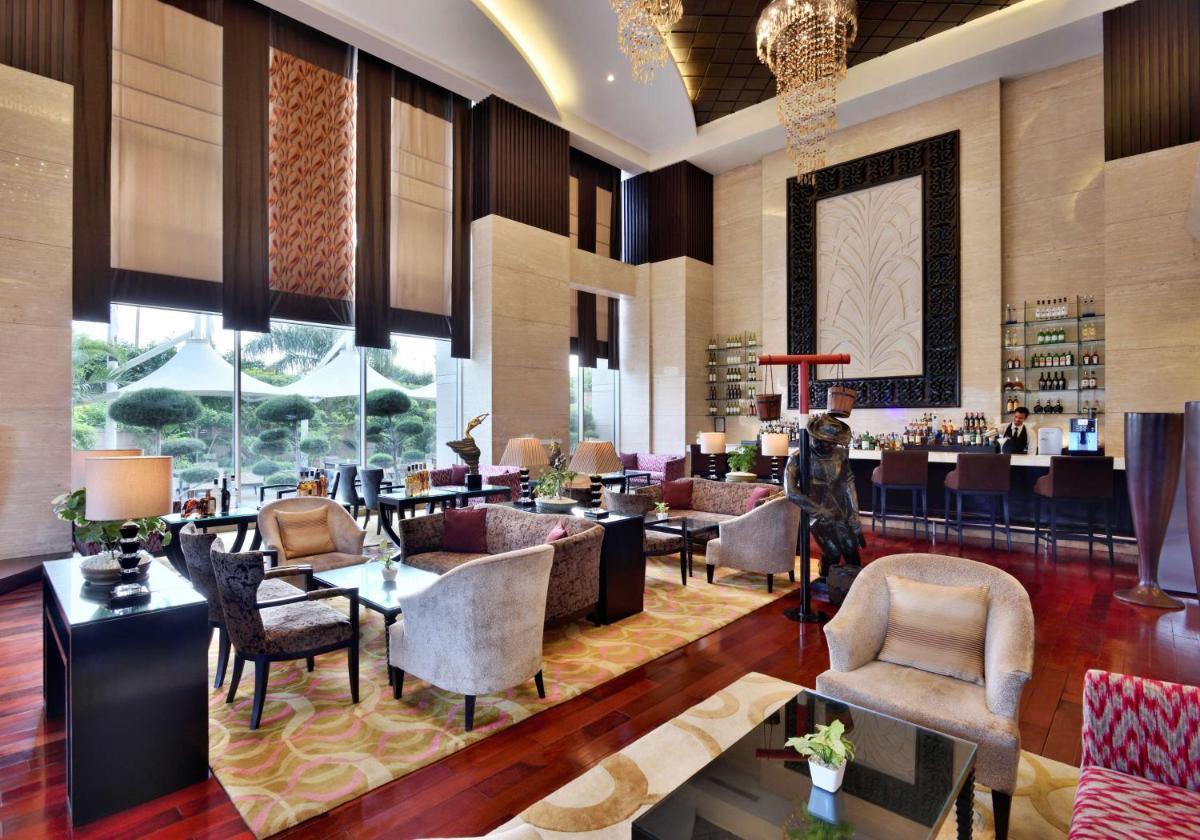 a lobby of a hotel with tables and chairs at Radisson Blu Hotel, Indore in Indore