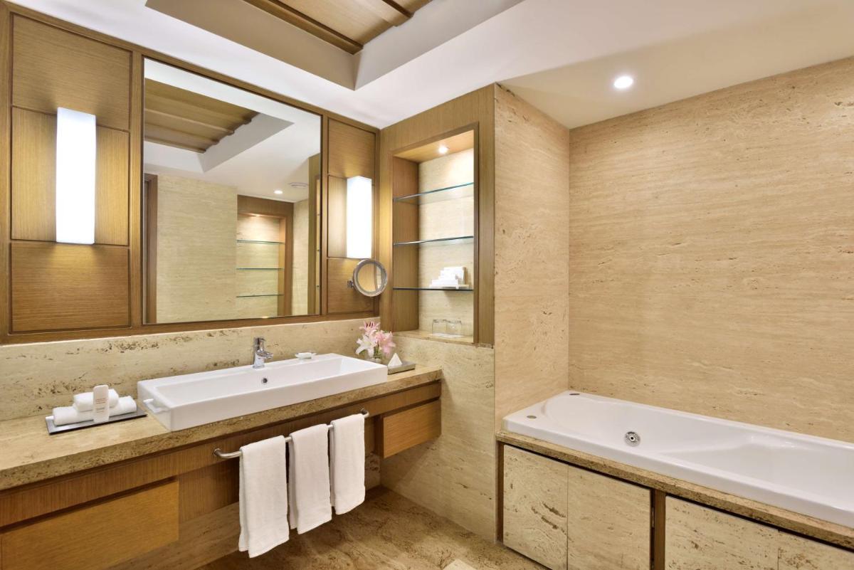 a bathroom with a sink and a tub and a mirror at Radisson Blu Hotel, Indore in Indore