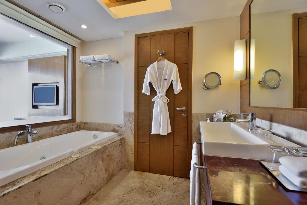 a bathroom with a bath tub and a robe hanging on a door at Radisson Blu Hotel, Indore in Indore