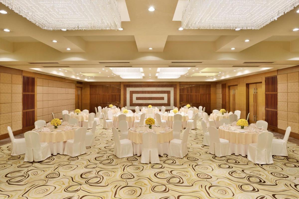 a banquet hall with white tables and chairs and a screen at Radisson Blu Hotel, Indore in Indore