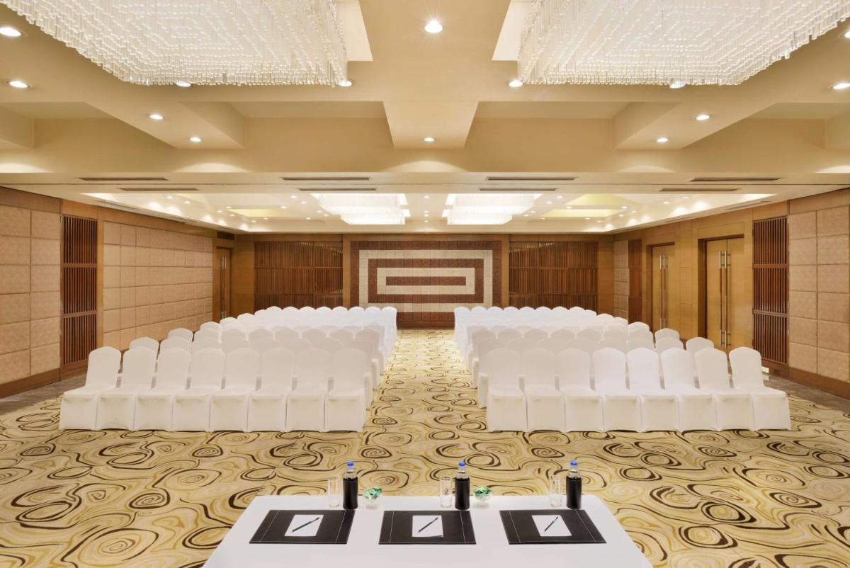a banquet hall with white chairs and a stage at Radisson Blu Hotel, Indore in Indore