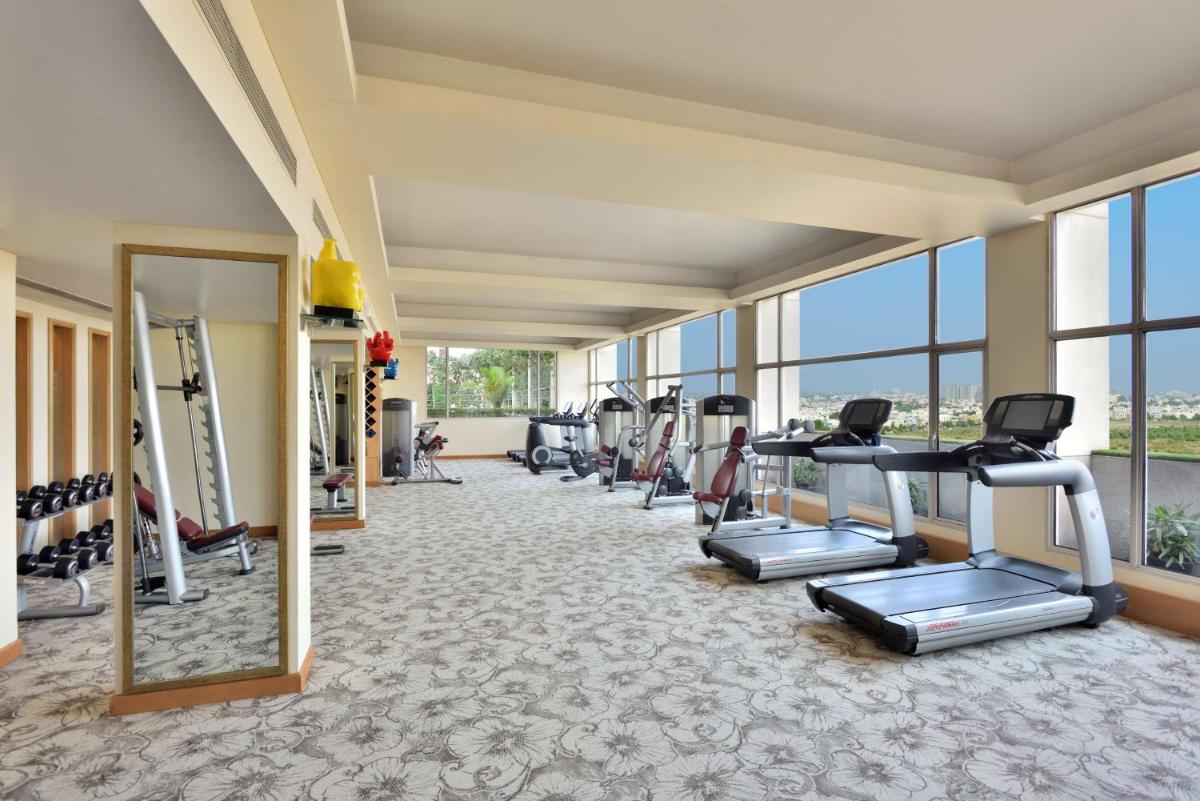 a gym with treadmills and ellipticals in a room with windows at Radisson Blu Hotel, Indore in Indore