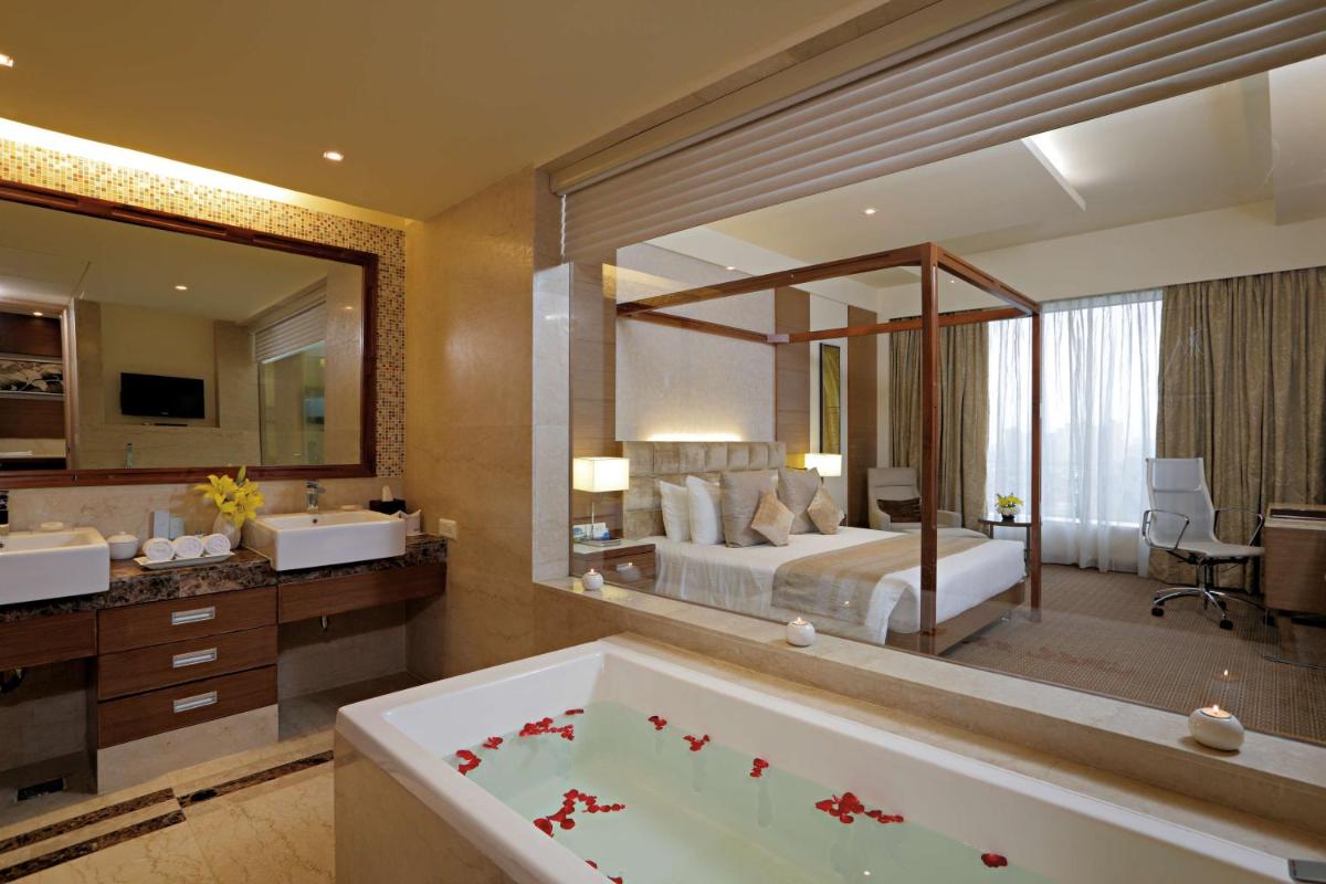a bathroom with a tub and a bedroom with a bed at Radisson Blu Hotel, Greater Noida in Greater Noida