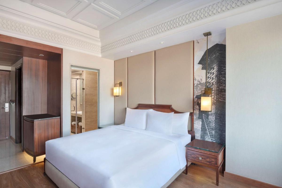 a bedroom with a large white bed and a desk at Radisson Kufri in Shimla
