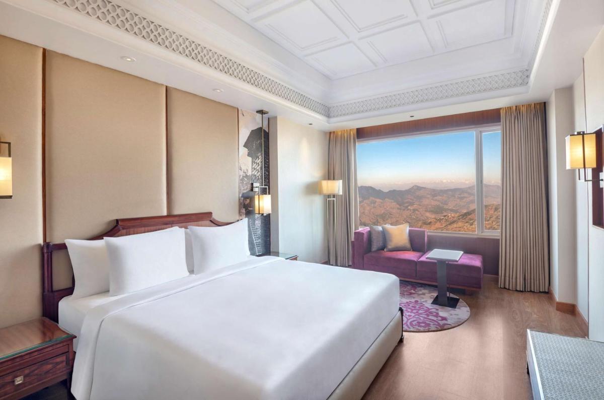 a bedroom with a large white bed and a window at Radisson Kufri in Shimla