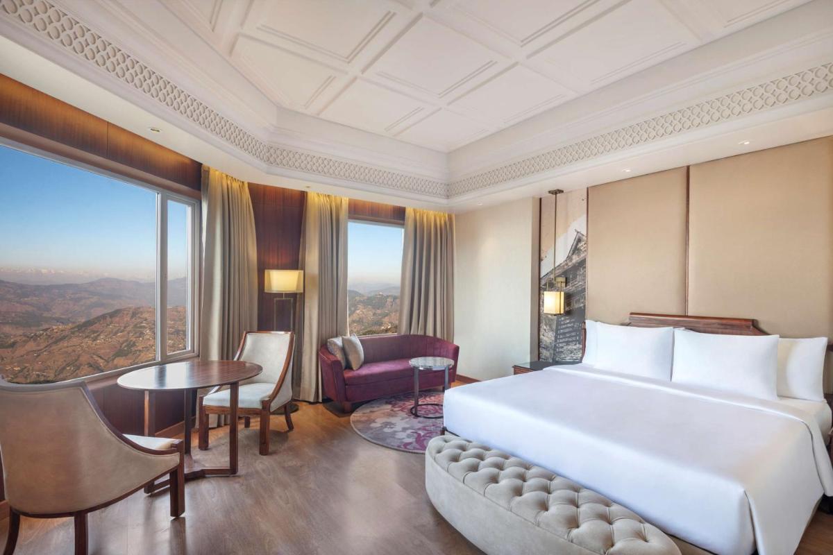 a bedroom with a large white bed and a table at Radisson Kufri in Shimla