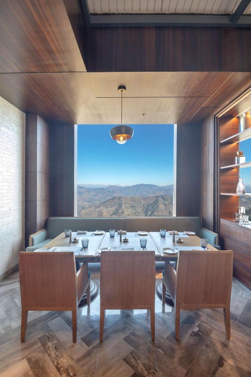 a dining room with a table and chairs and a large window at Radisson Kufri in Shimla