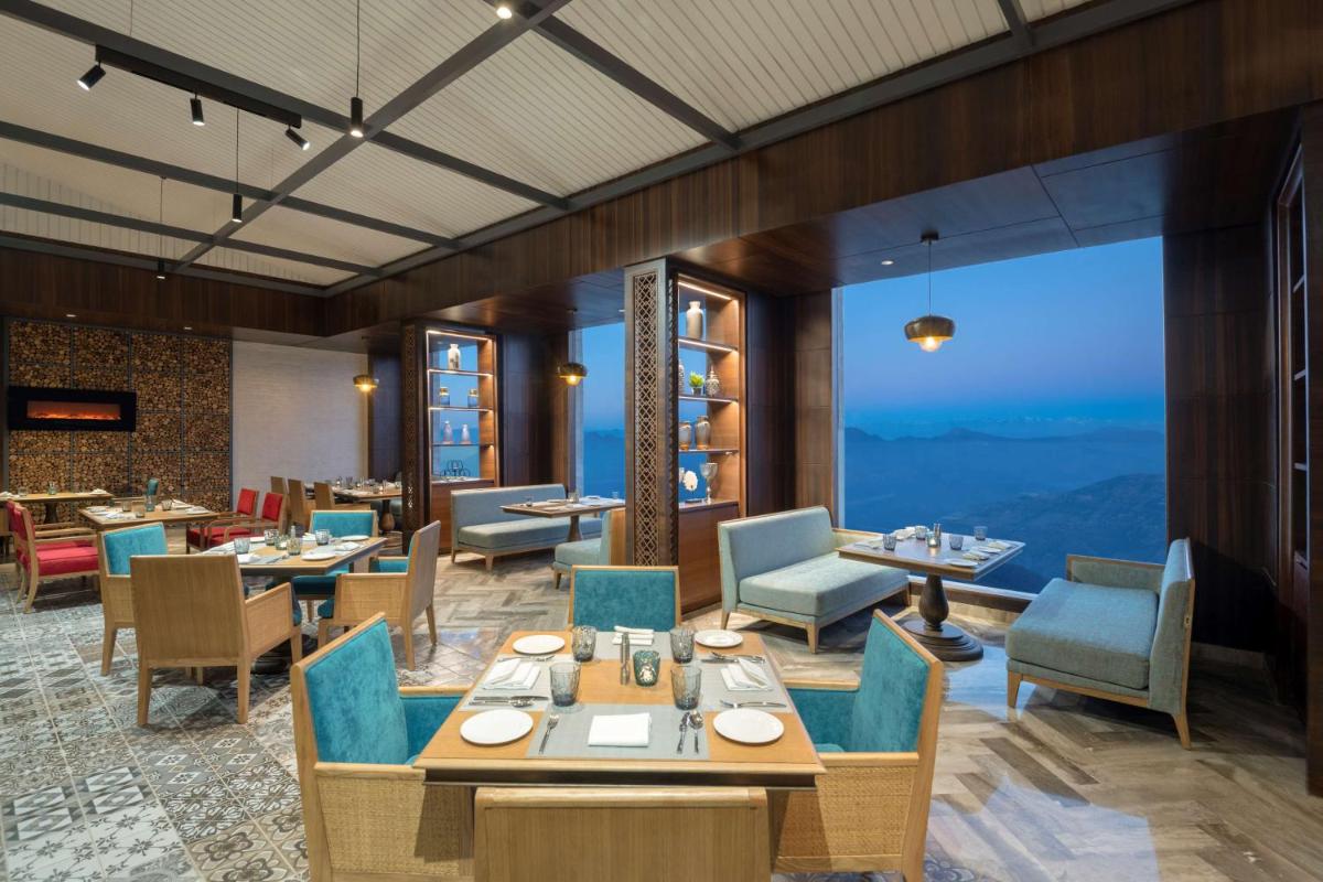 a restaurant with tables and chairs and a large window at Radisson Kufri in Shimla