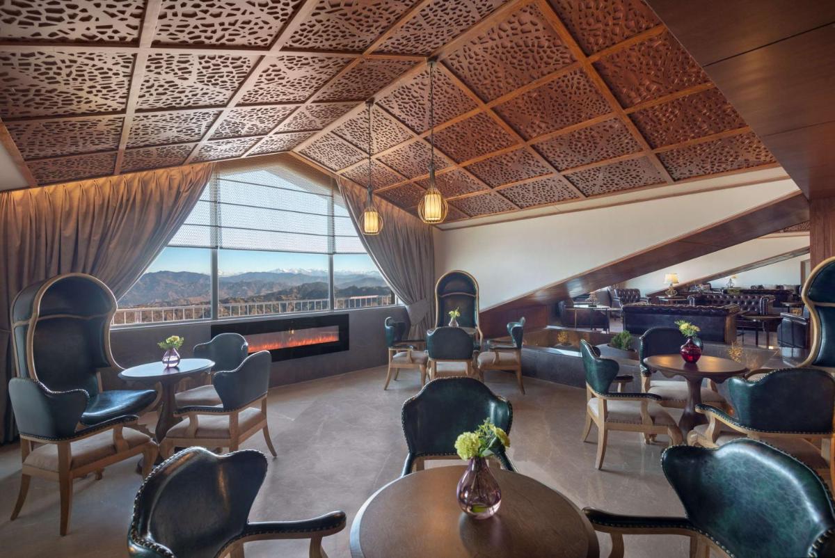 a restaurant with tables and chairs and a large window at Radisson Kufri in Shimla
