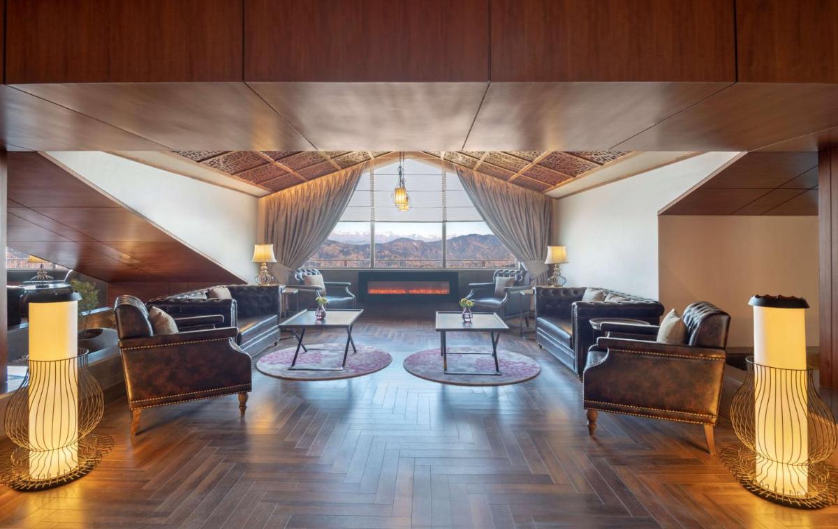 a living room with furniture and a large window at Radisson Kufri in Shimla