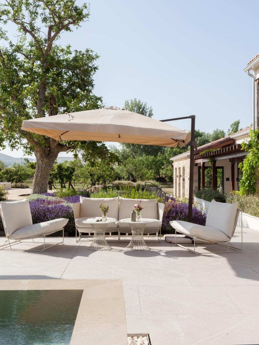 Una mesa y sillas bajo una sombrilla junto a una piscina. en Quinta San Francisco, en Castrojeriz
