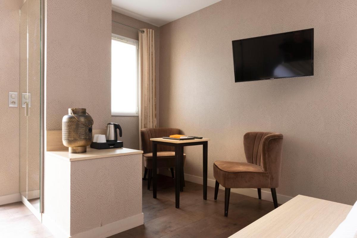 une chambre d'hôtel avec une table et deux chaises dans l'établissement Hostellerie de la Renaissance, à Argentan