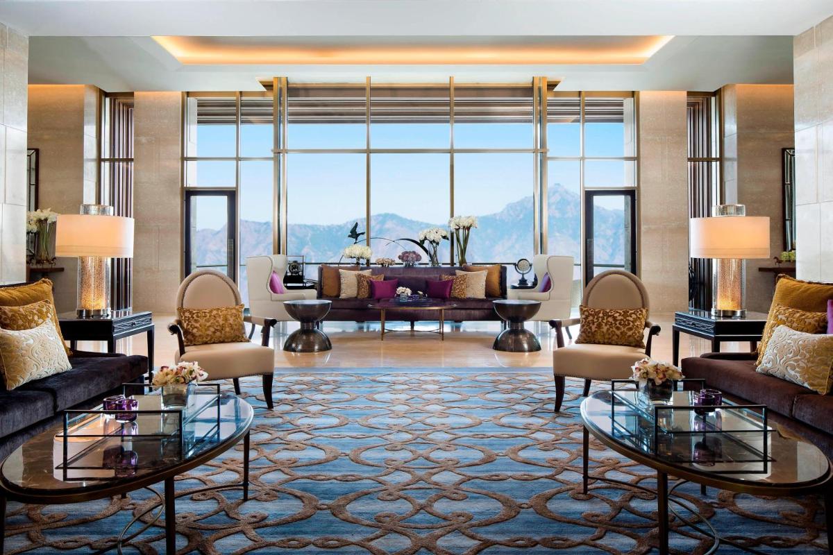 a living room with couches and a large window at JW Marriott Mussoorie Walnut Grove Resort & Spa in Mussoorie