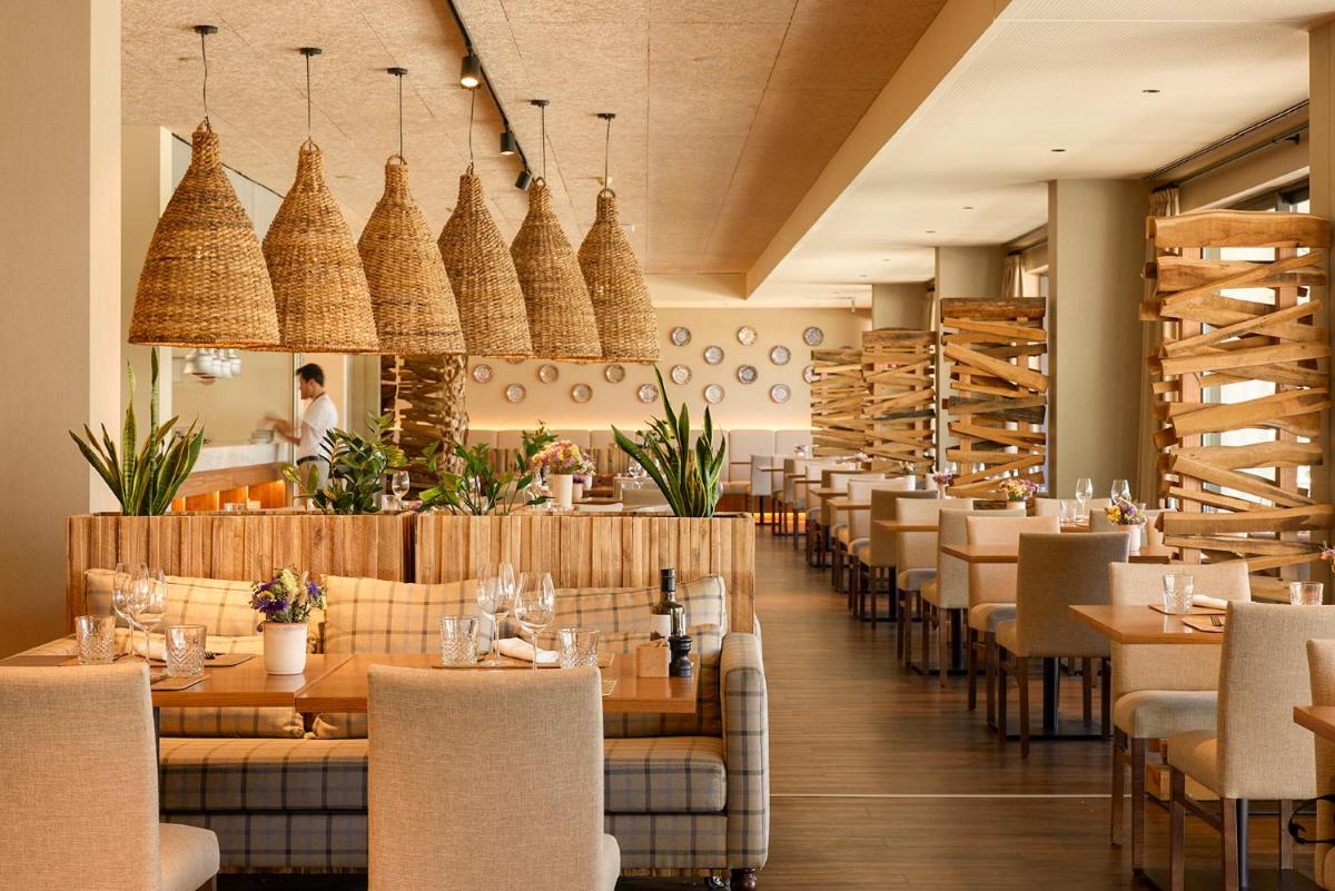 Um restaurante com mesas e cadeiras e uma mulher ao fundo. em Octant Evora em Évora