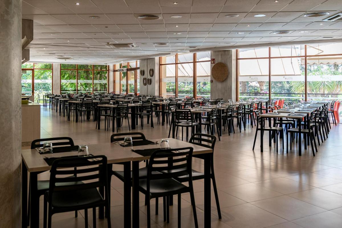 Un comedor con mesas y sillas y ventanas. en Intelier Orange, en Benicàssim