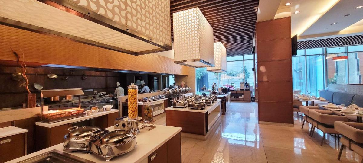 a restaurant with a large kitchen with tables and chairs at Radisson Blu Hotel, Greater Noida in Greater Noida