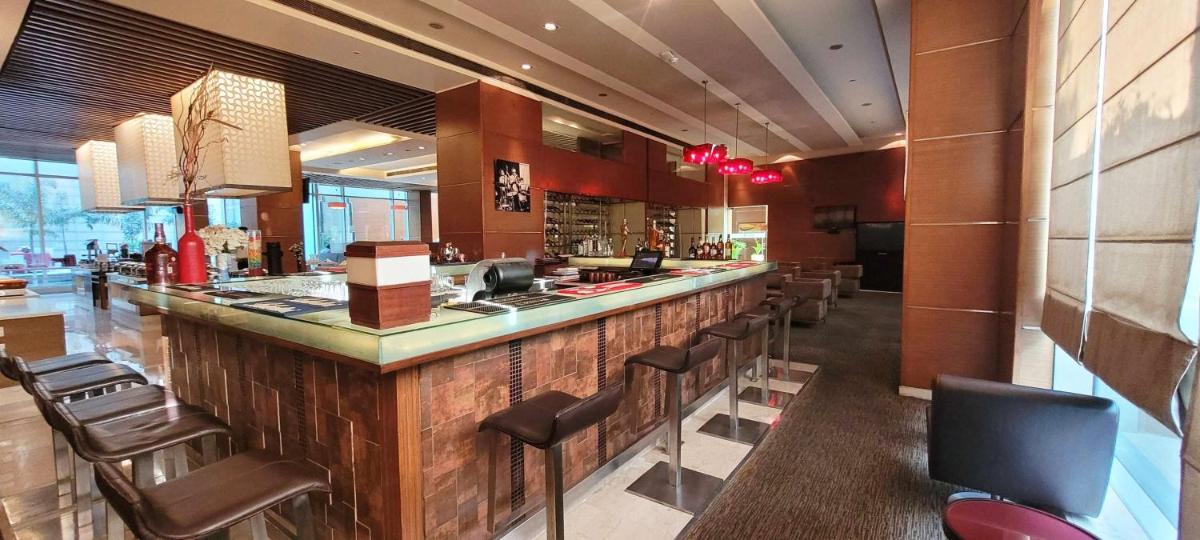 a restaurant with a bar with leather chairs at Radisson Blu Hotel, Greater Noida in Greater Noida