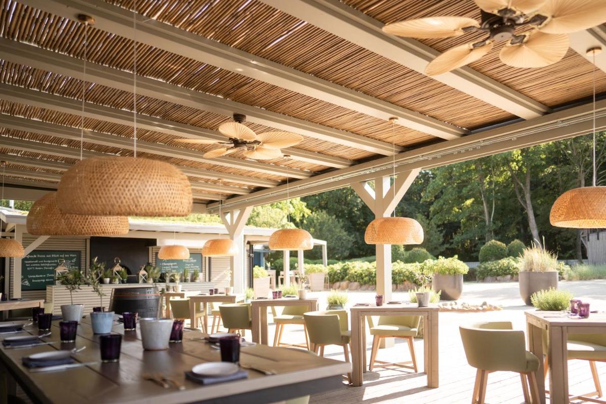 ein Restaurant mit Tischen, Stühlen und Deckenventilatoren in der Unterkunft Weissenhaus Private Nature Luxury Resort in Weißenhaus