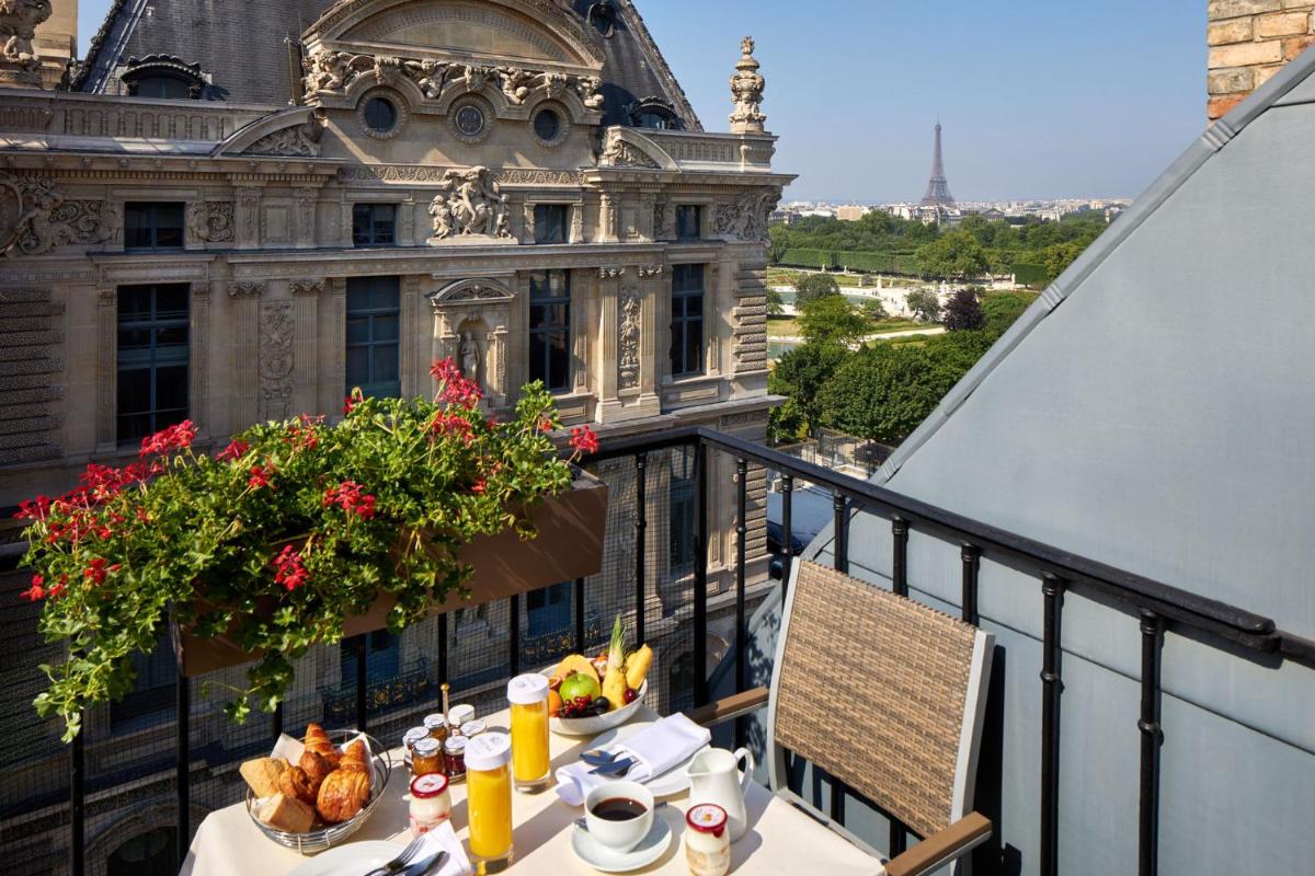 - une table avec de la nourriture sur un balcon avec un bâtiment dans l'établissement Hôtel Regina Louvre, à Paris