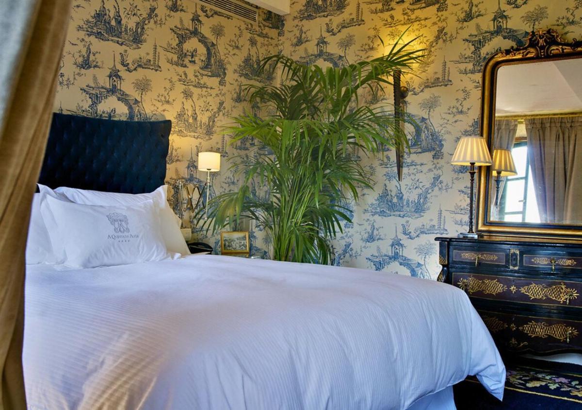 Un dormitorio con una cama blanca y un espejo. en A Quinta Da Auga Hotel Spa Relais & Chateaux, en Santiago de Compostela