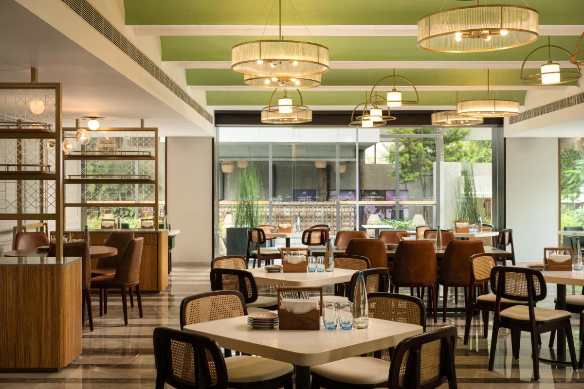 a dining room with tables and chairs and a restaurant at Grand Mercure Bangalore - An Accor Brand in Bengaluru