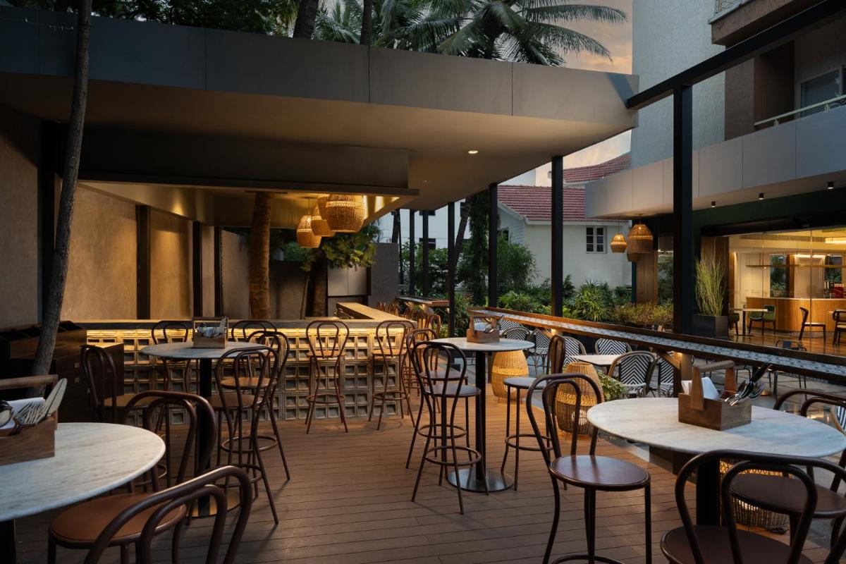 a restaurant with tables and chairs on a patio at Grand Mercure Bangalore - An Accor Brand in Bengaluru a restaurant with tables and chairs on a patio at Grand Mercure Bangalore - An Accor Brand in Bengaluru