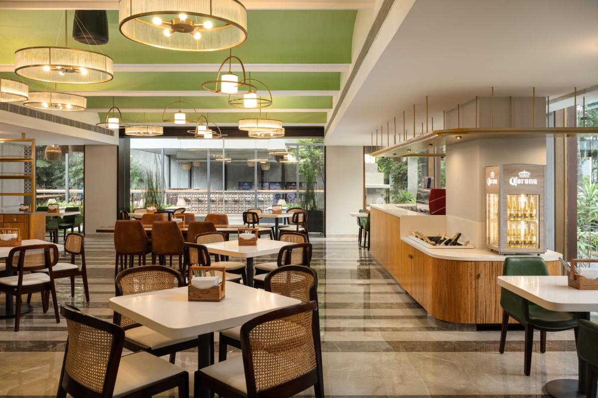 a restaurant with tables and chairs and a cafeteria at Grand Mercure Bangalore - An Accor Brand in Bengaluru