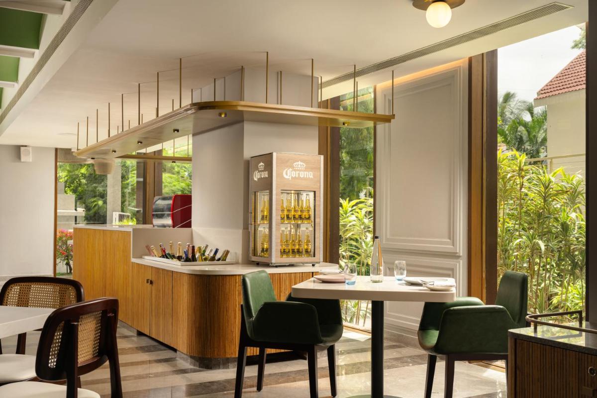 a restaurant with a bar with green chairs and a table at Grand Mercure Bangalore - An Accor Brand in Bengaluru