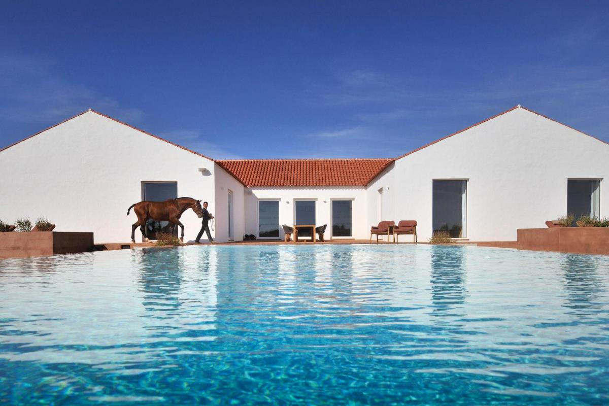 um cavalo parado em frente a uma casa com piscina em Herdade da Malhadinha Nova - Relais & Châteaux em Albernoa