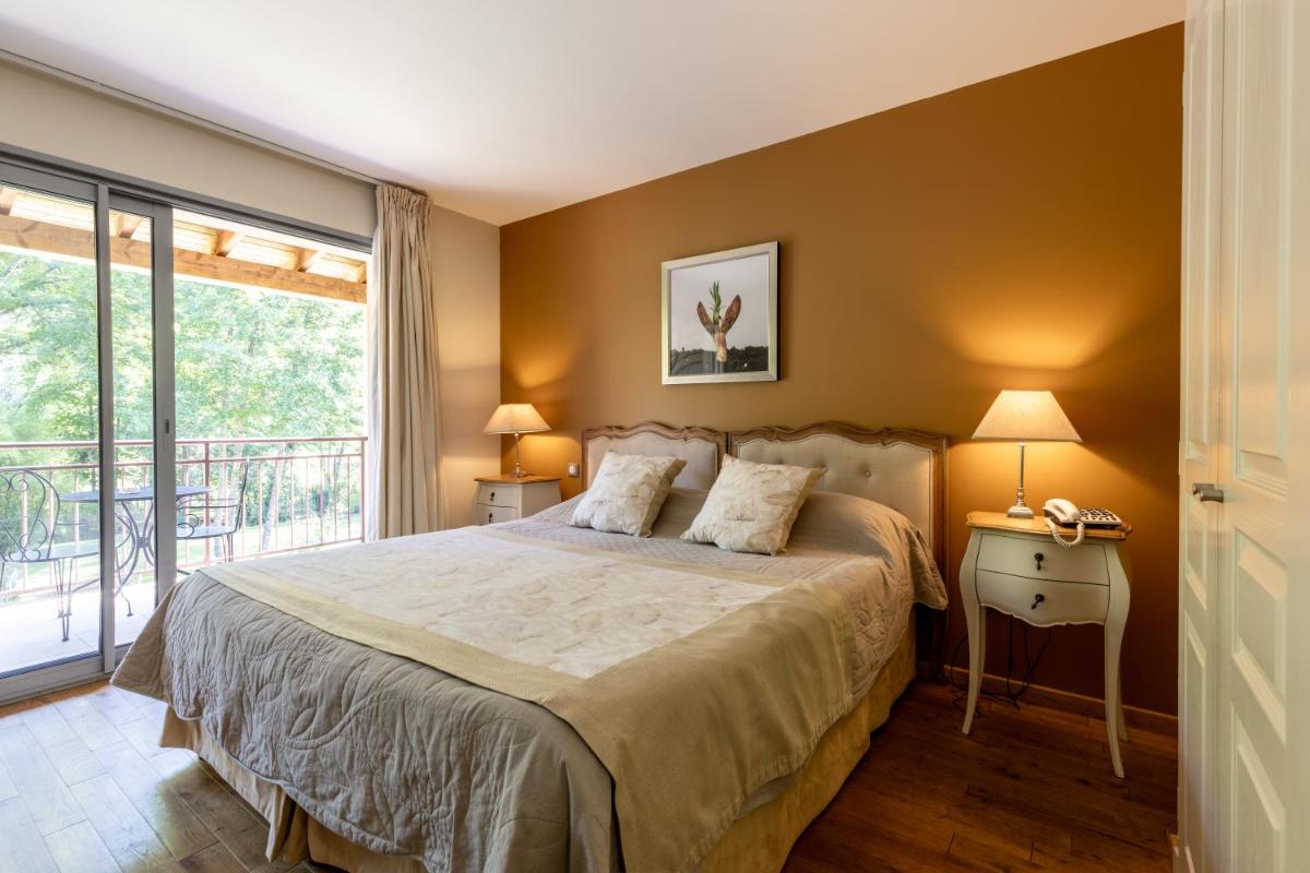 une chambre avec un lit et un balcon dans l'établissement Le Moulin de Mitou, à Auriac-du-Périgord