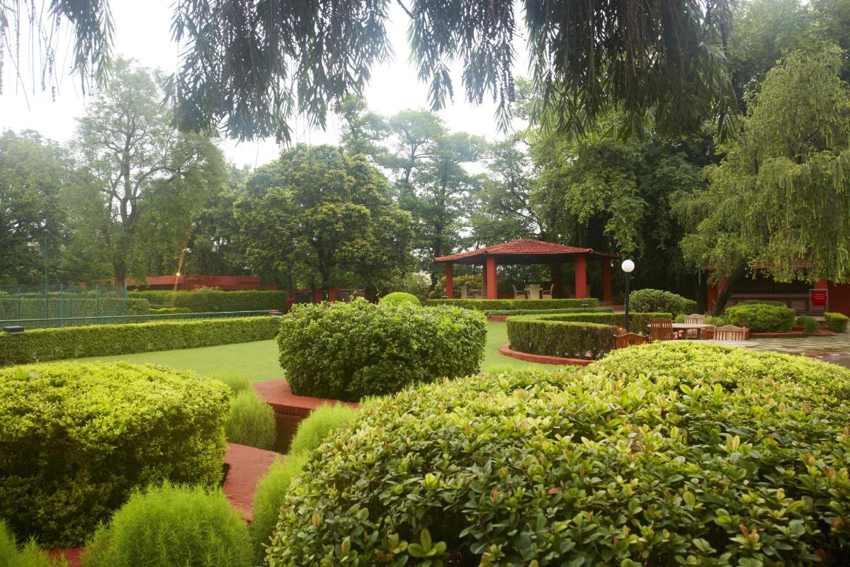 a garden with a gazebo and some bushes and trees at Taj Ganges Varanasi in Varanasi