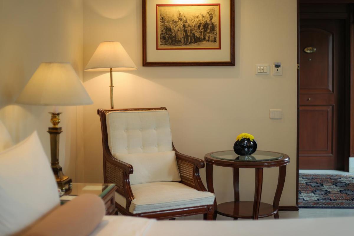 a hotel room with a chair and a table at The Imperial, New Delhi in New Delhi a hotel room with a chair and a table at The Imperial, New Delhi in New Delhi