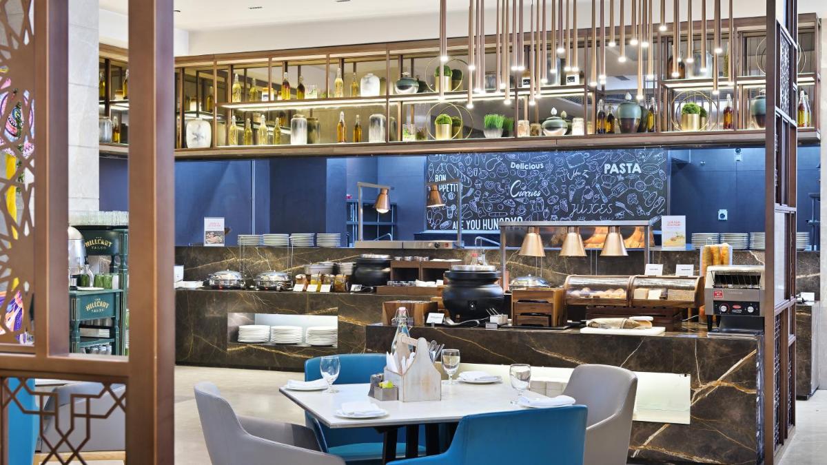 a restaurant with blue walls and a table and chairs at Holiday Inn Gurugram Sector 90 by IHG in Gurgaon