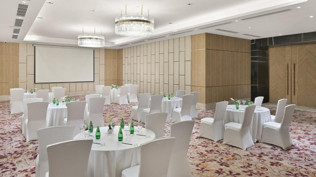 a conference room with white tables and chairs and a screen at Holiday Inn Gurugram Sector 90 by IHG in Gurgaon +161 photos