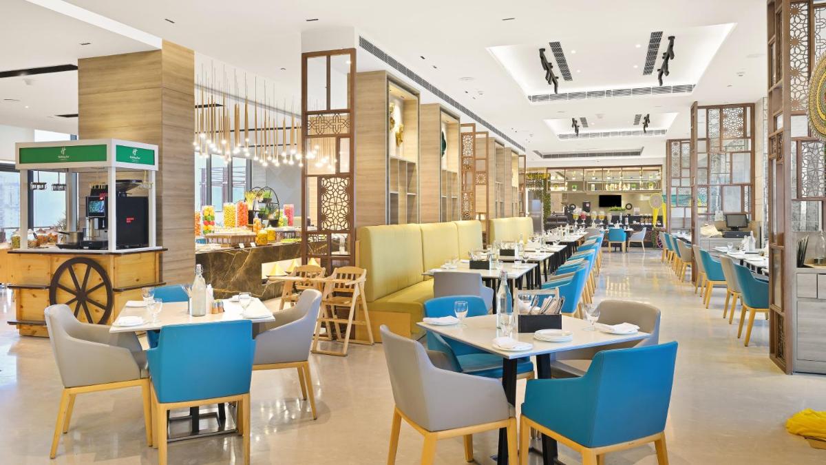 a restaurant with tables and chairs and a cafeteria at Holiday Inn Gurugram Sector 90 by IHG in Gurgaon