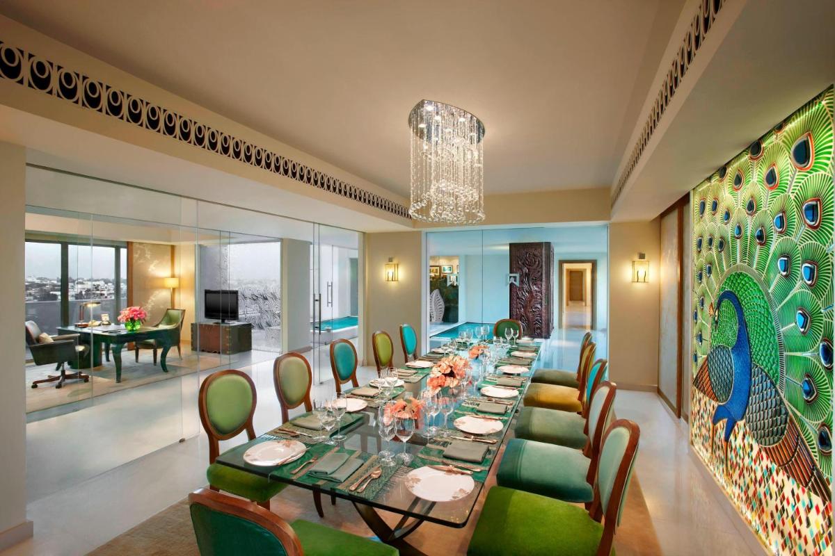a dining room with a long table and green chairs at ITC Gardenia, a Luxury Collection Hotel, Bengaluru in Bengaluru a dining room with a long table and green chairs at ITC Gardenia, a Luxury Collection Hotel, Bengaluru in Bengaluru