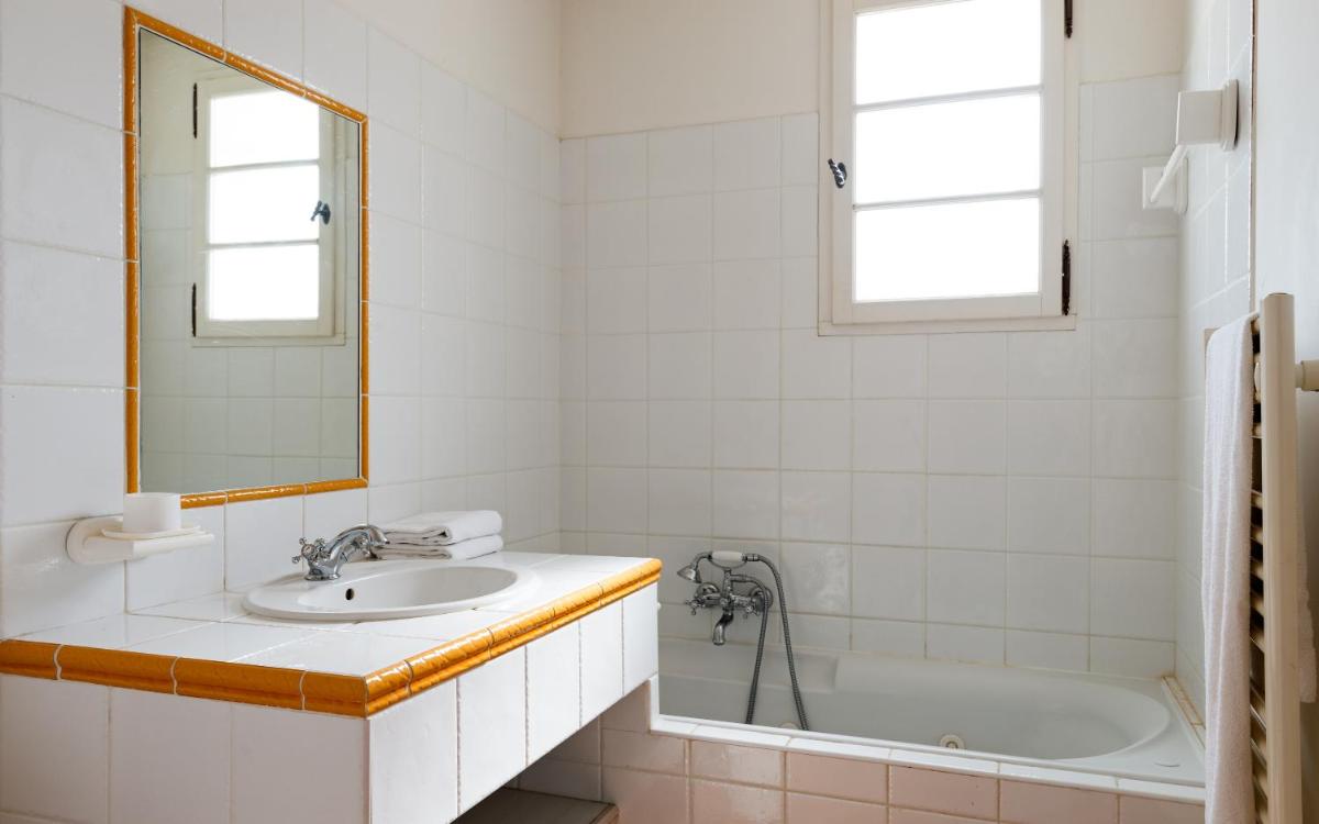 une salle de bain avec un lavabo, une baignoire et un miroir dans l'établissement Lagrange Vacances Domaine de Fayence, à Fayence