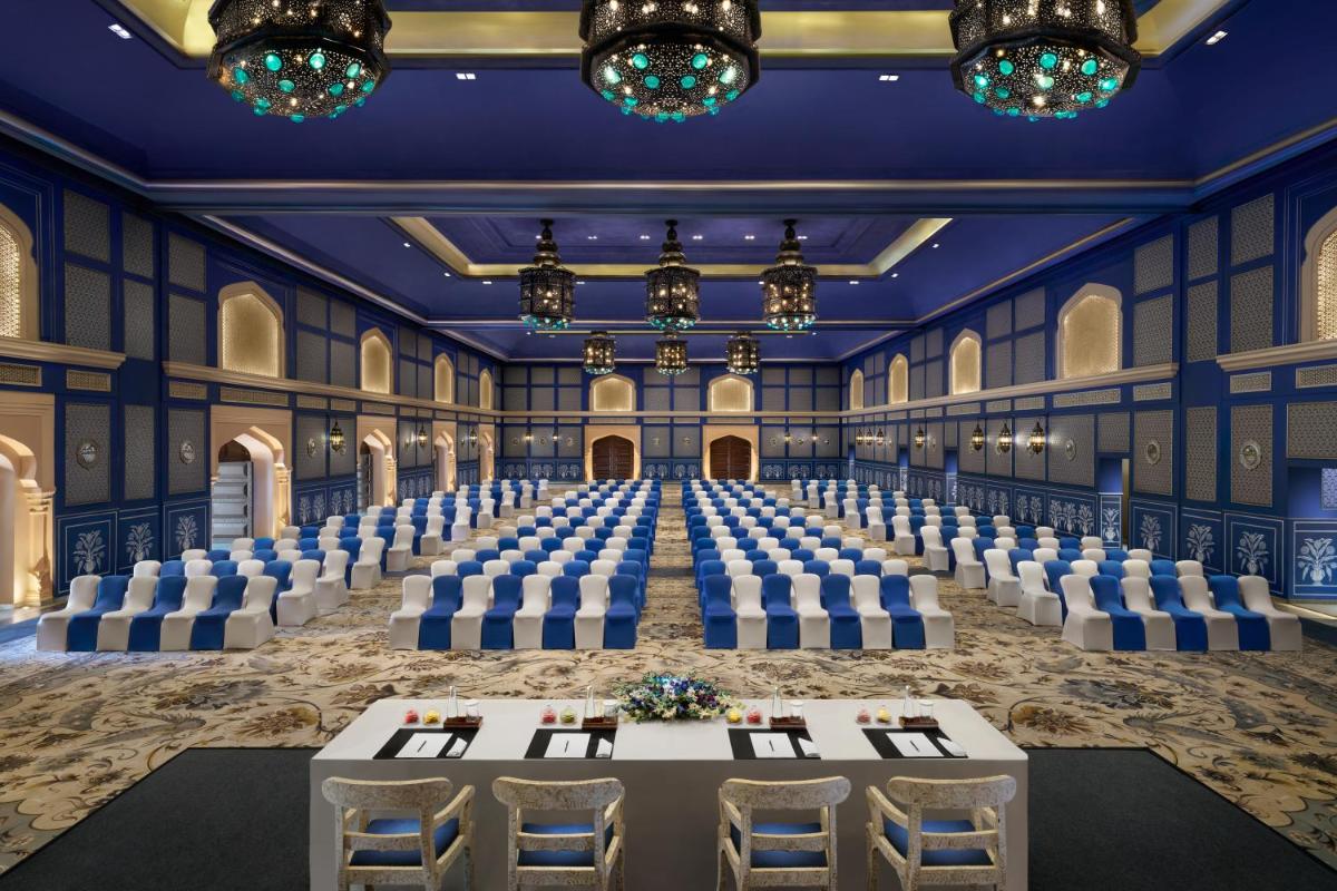 a banquet hall with tables and chairs and chandeliers at Fairmont Jaipur in Jaipur