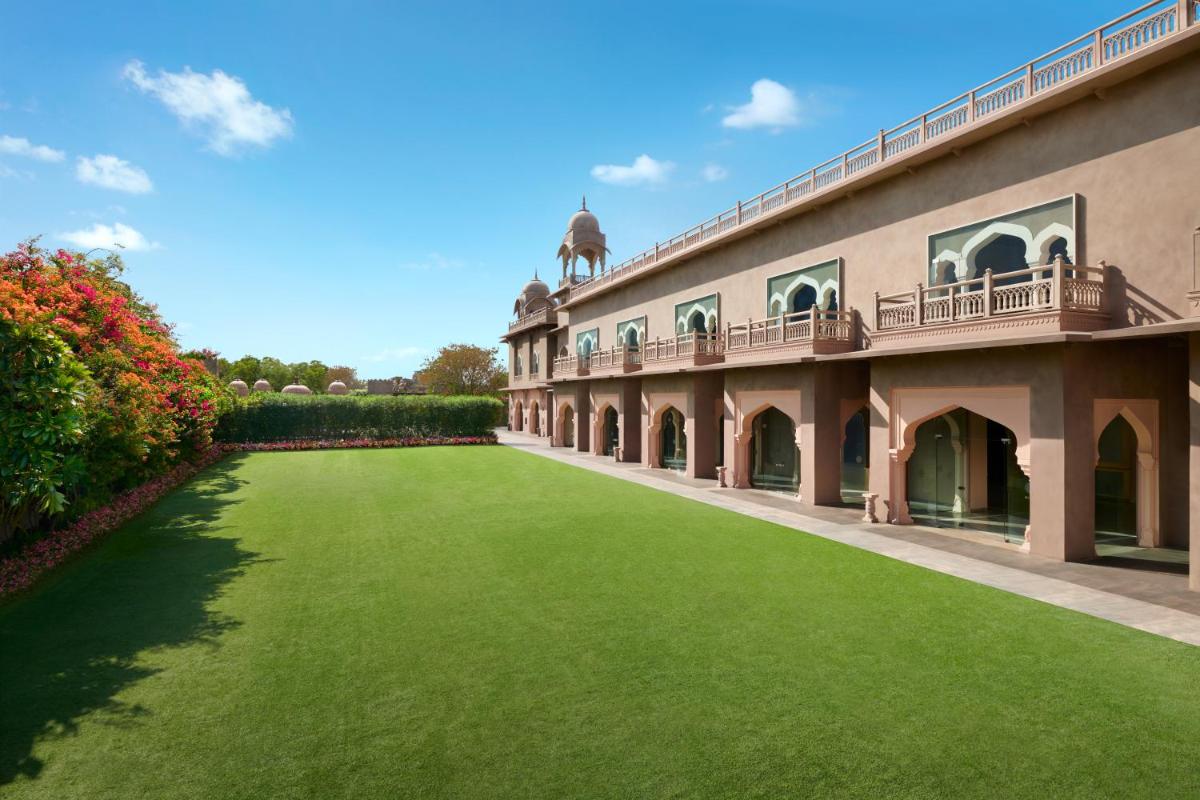 a large building with a green lawn in front of it at Fairmont Jaipur in Jaipur
