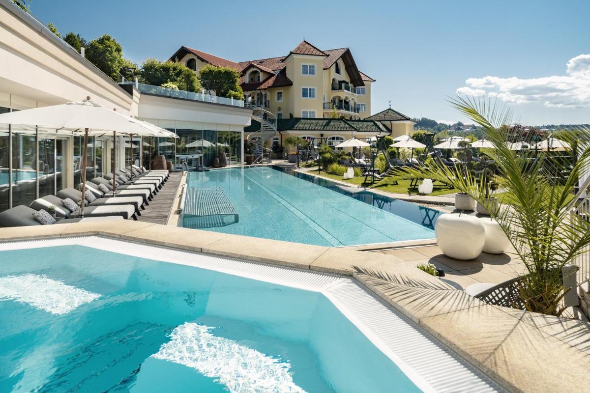 ein Swimmingpool mit Liegestühlen und ein Haus in der Unterkunft Wellness- & Sporthotel Jagdhof in Röhrnbach