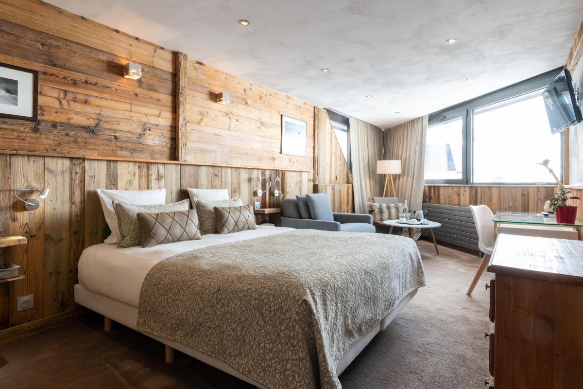 une chambre avec un grand lit et des murs en bois dans l'établissement Hotel 3 Vallées Val Thorens, à Val Thorens