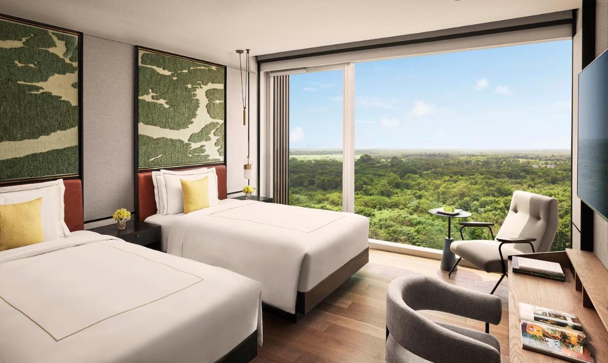 a hotel room with two beds and a large window at Taj The Trees, Mumbai in Mumbai