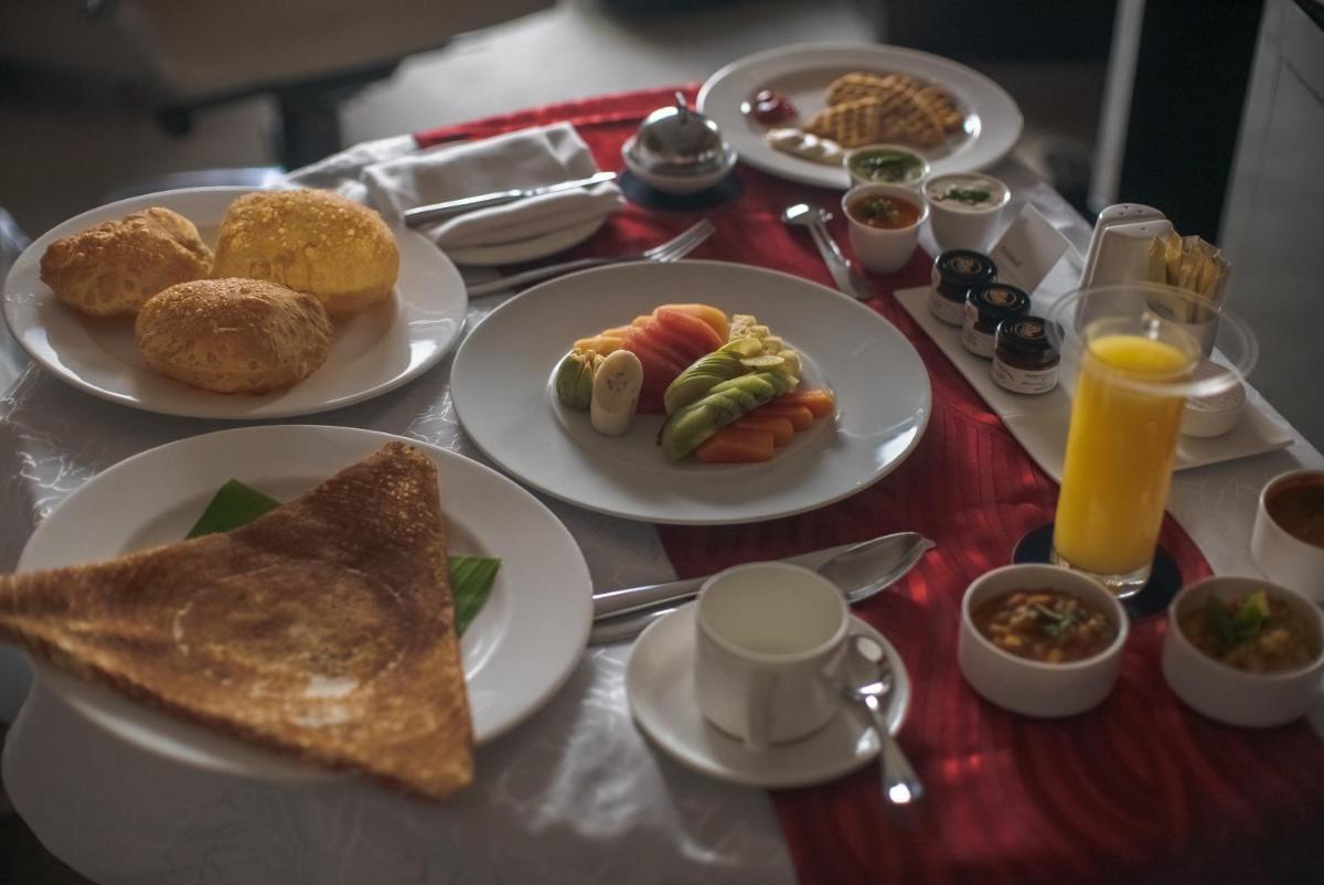 a table topped with plates of breakfast foods and orange juice at Sheraton Grand Bangalore Hotel at Brigade Gateway in Bengaluru