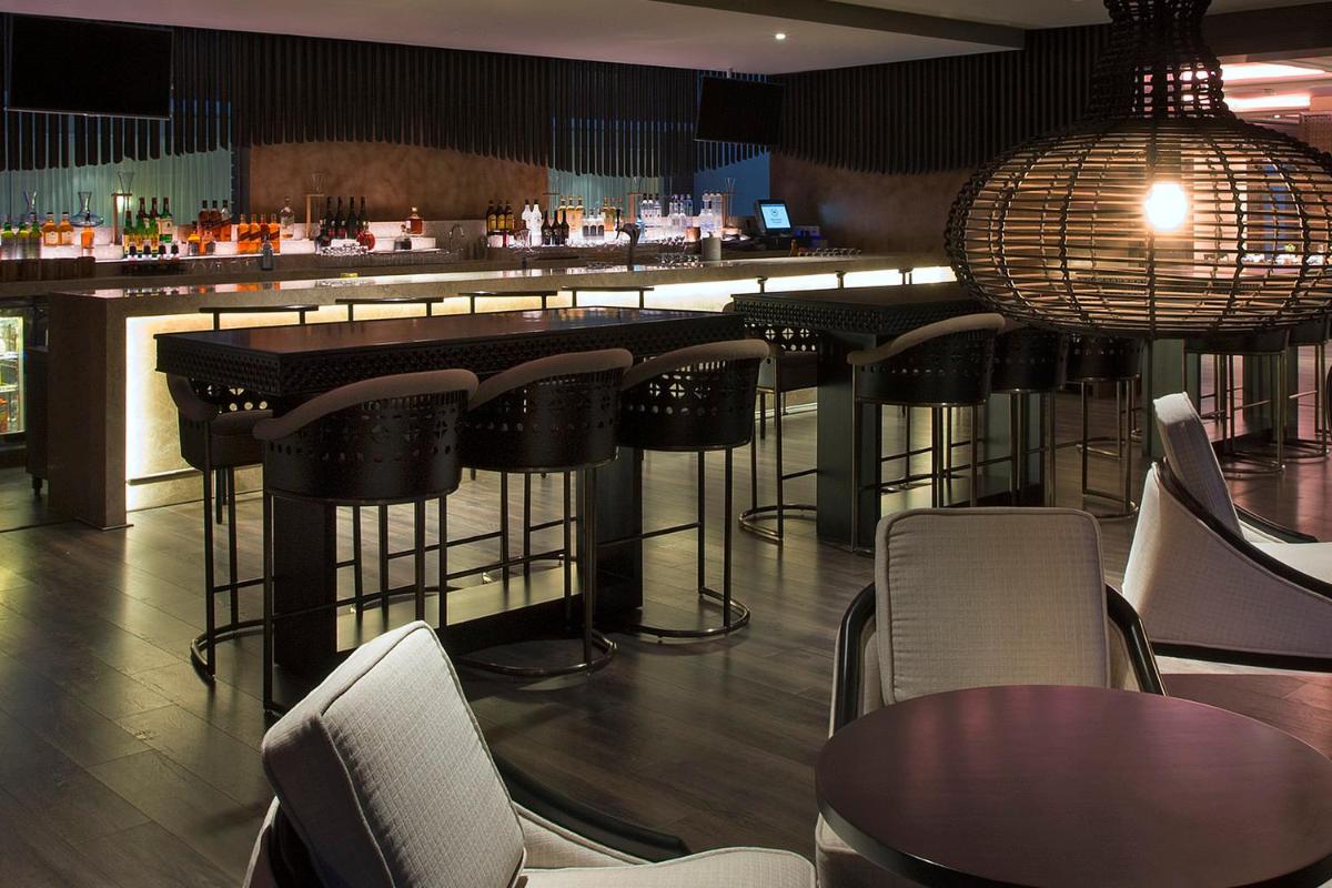 a bar with chairs and tables in a restaurant at Sheraton Hyderabad Hotel in Hyderabad