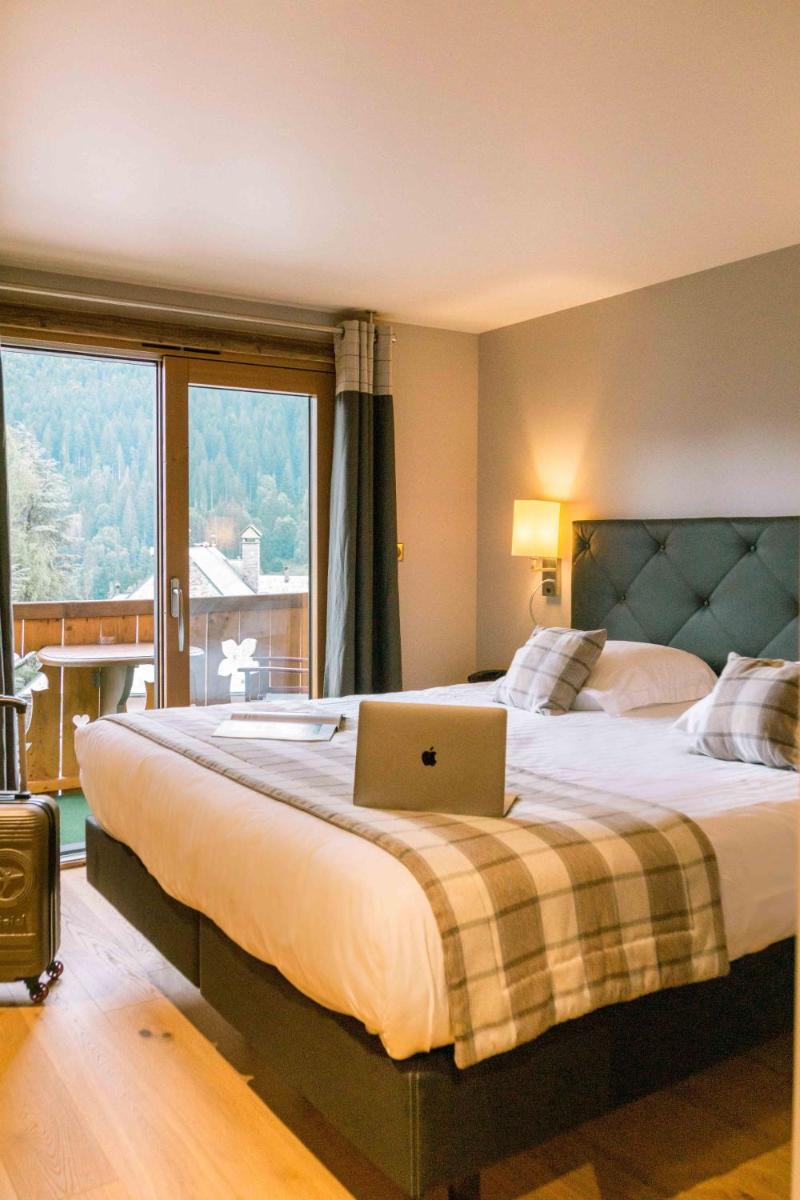une chambre avec un lit sur lequel se trouve un ordinateur portable dans l'établissement Les Gentianettes Hotel & Spa, à La Chapelle-dʼAbondance