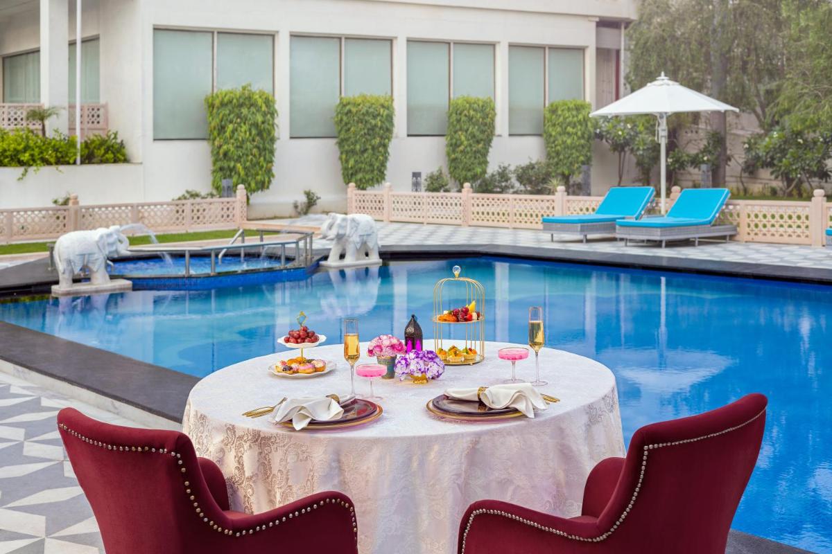 a table with food and drinks in front of a pool at Tajview, Agra-IHCL SeleQtions in Agra