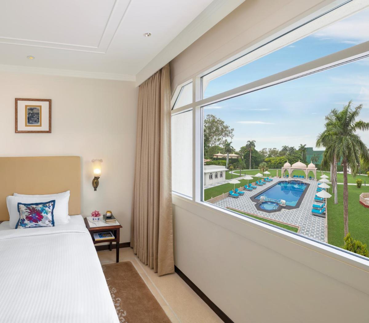 a bedroom with a bed and a window with a view of a pool at Tajview, Agra-IHCL SeleQtions in Agra