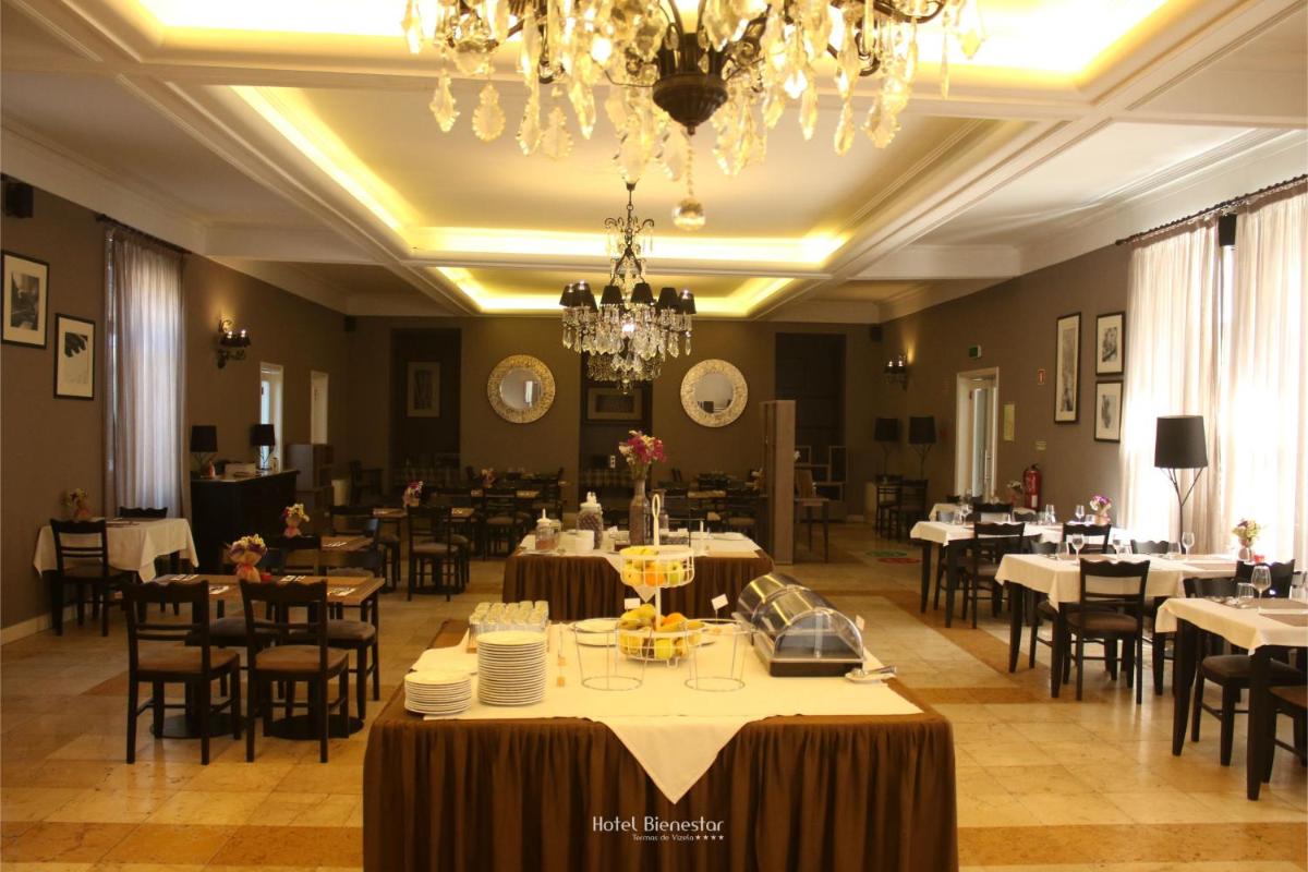 uma sala de jantar com mesas e cadeiras e um lustre em Hotel Bienestar Termas De Vizela em Vizela mais 69 fotografias